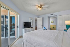 A hotel room with a large bed, a television, a ceiling fan, and a sliding glass door to an outdoor area.
