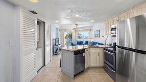 Una cocina moderna con electrodomésticos de acero inoxidable, una isla central y vistas a una sala de estar.