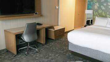 Una habitación de hotel con una cama, un escritorio con una silla, un televisor y una mesita de noche.