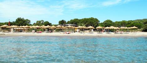 Una playa con aguas cristalinas, sombrillas y una orilla arenosa.
