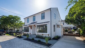 Et moderne hus med to etager, et stort vindue mod haven, en overdækket veranda og solcelle på taget.