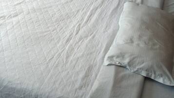 A bed with a quilted white bedspread and two pillows.