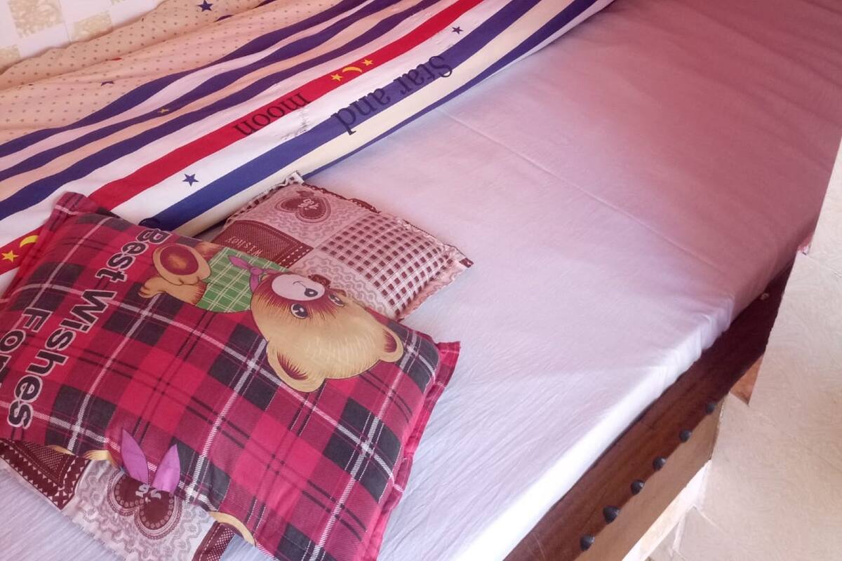 Ein Bett mit gestreifter Bettwäsche und einem Kopfkissen mit Bär-Motiv.
