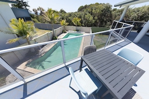 Un balcón con piscina, una mesa y una silla.