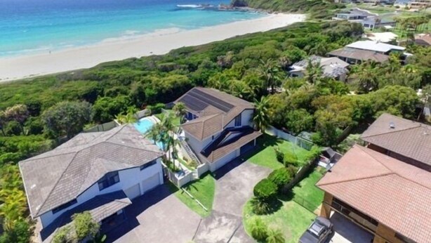 Una zona residenziale costiera con case, una spiaggia e un paesaggio collinare.