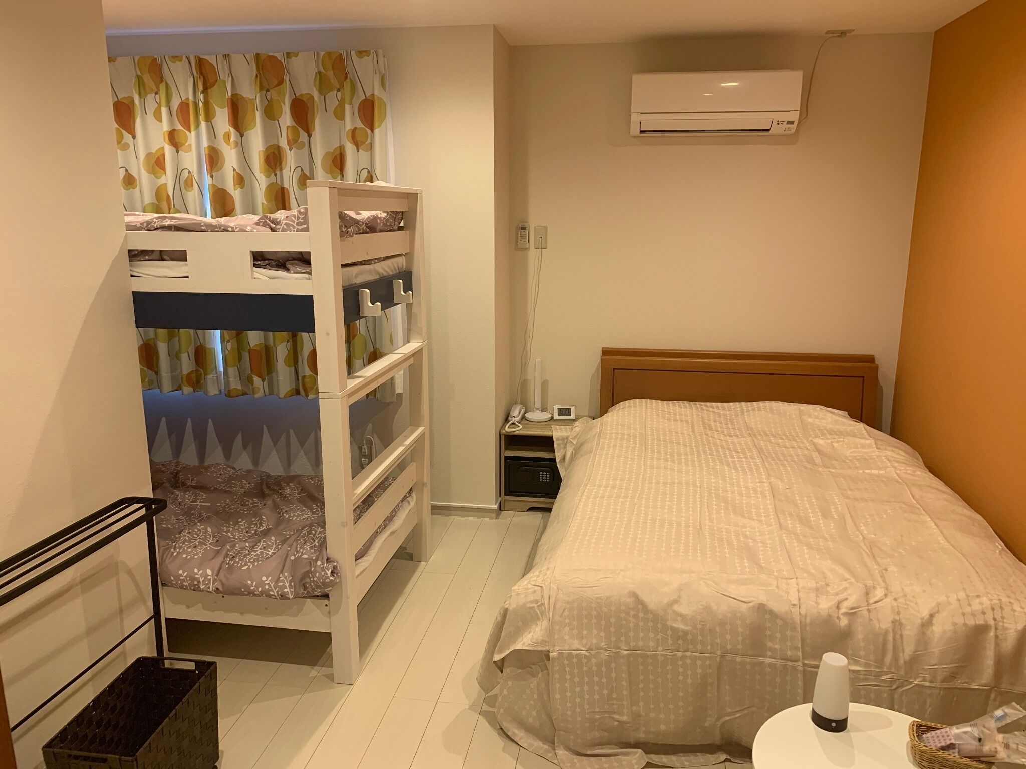 A bedroom with bunk beds, a bedside table, a lamp, an air conditioner, and a bedside phone.