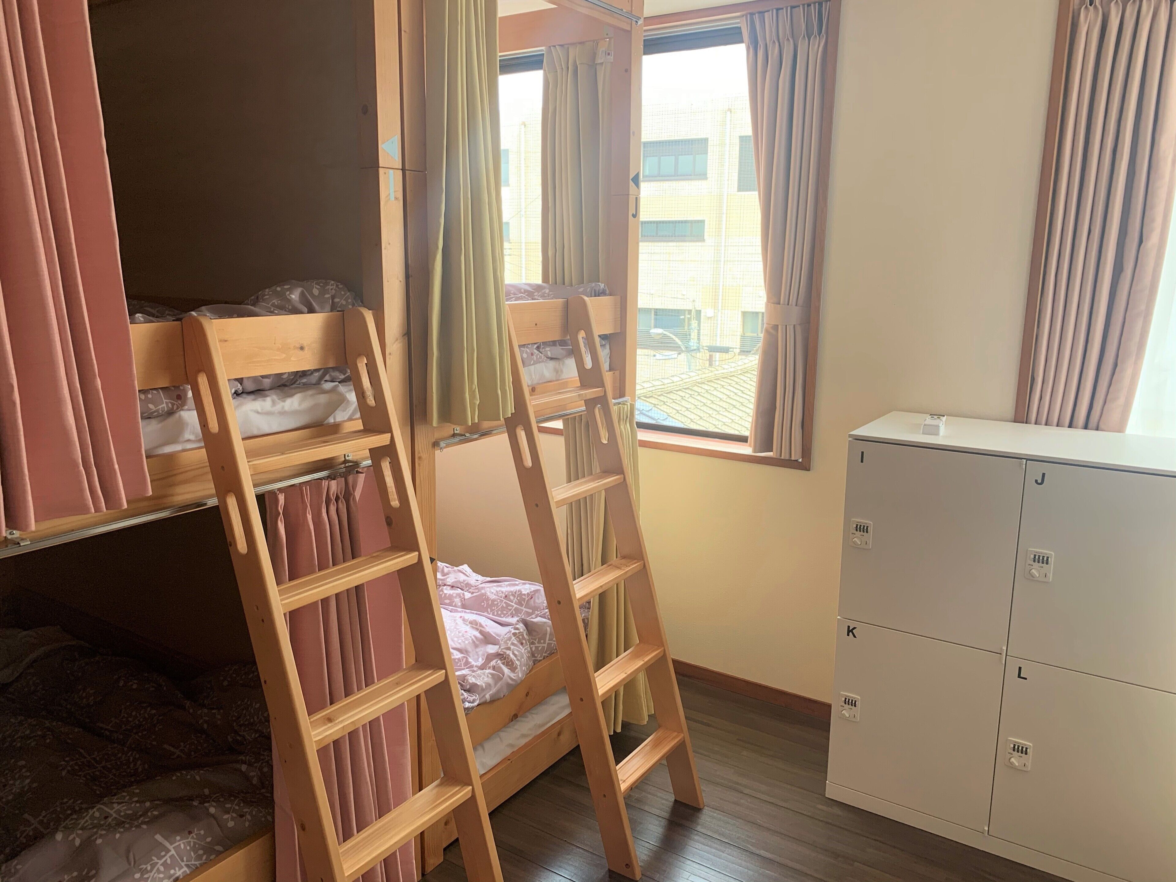 A room with bunk beds, a ladder, a window with curtains, and a white cabinet.