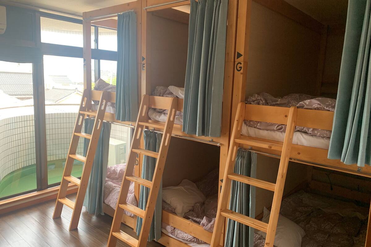 Um quarto de dormitório com beliches, escadas de madeira e cortinas.
