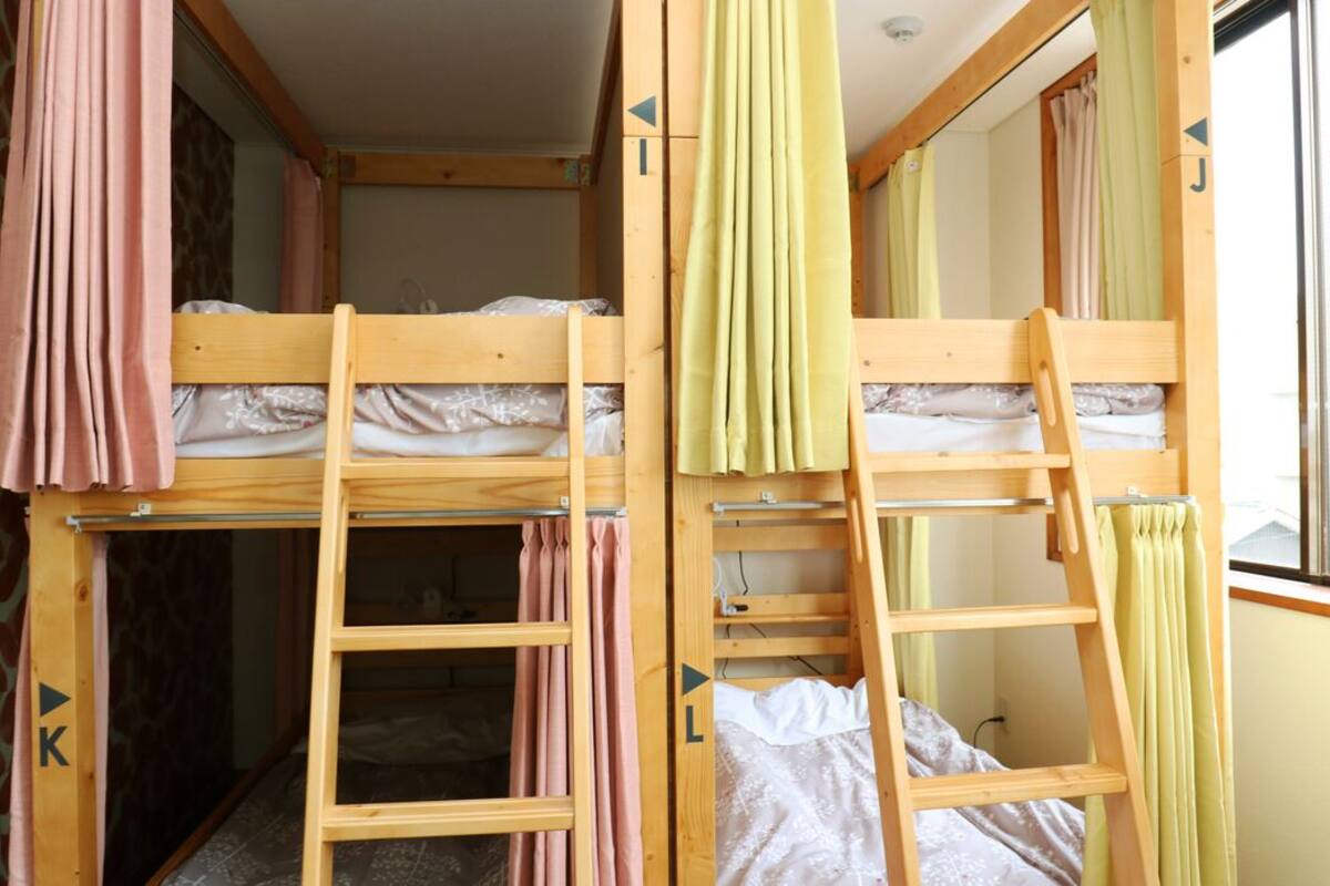 Quarto com beliche, escada, cortinas e janela.