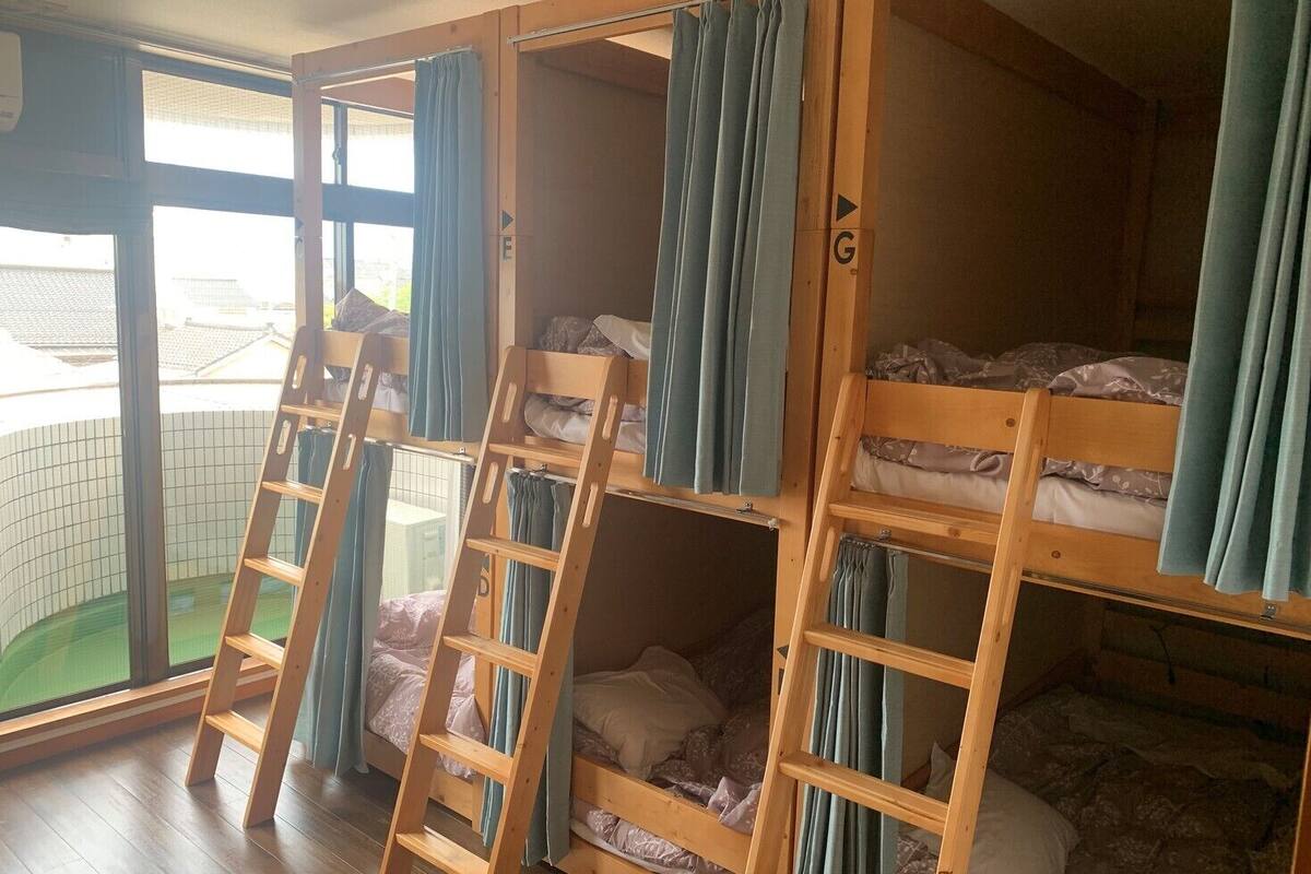 Quarto de dormitório com beliches, escadas de madeira e cortinas.