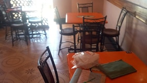 A restaurant interior with patterned floor tiles, wooden chairs, and tables. - Esidai Hotel (Mai Mahiu)