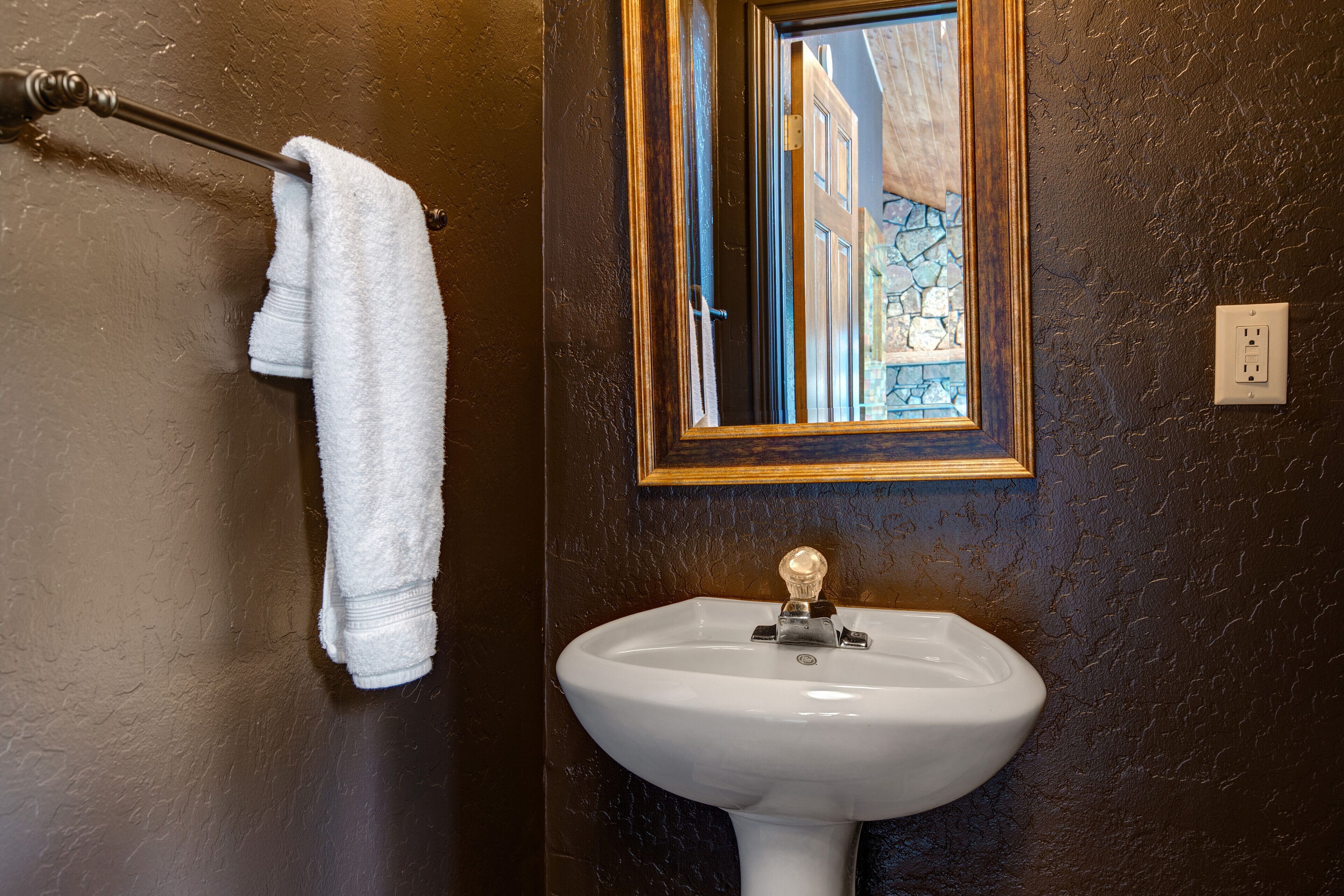 A bathroom with a white sink, a towel hanging on a rack, and a window with a view of buildings.