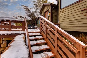Una escalera de madera con nieve en los peldaños que conduce a un edificio con el número 225.