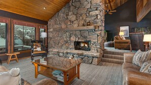 Una sala de estar acogedora con chimenea de piedra, sofás de cuero y una mesa de centro de madera.