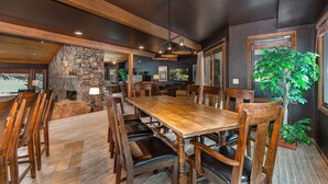 Un comedor amplio con una gran mesa de madera y sillas, detalles de piedra y un ventanal con vistas.