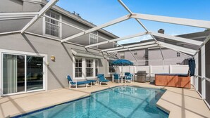 A swimming pool with blue tiles, surrounded by a covered patio area with blue chairs and a table. - Luxury Villa with private  pool and heated Jacuzzi (Kissimmee)
