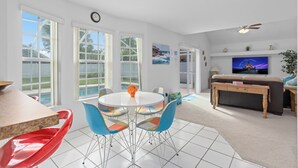 A spacious living area with a round table, colorful chairs, a television, and a ceiling fan. - Luxury Villa with private  pool and heated Jacuzzi (Kissimmee)