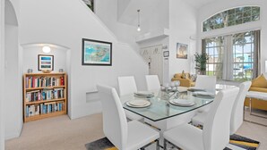 A modern dining area with a glass table, white chairs, and a bookshelf. - Luxury Villa with private  pool and heated Jacuzzi (Kissimmee)