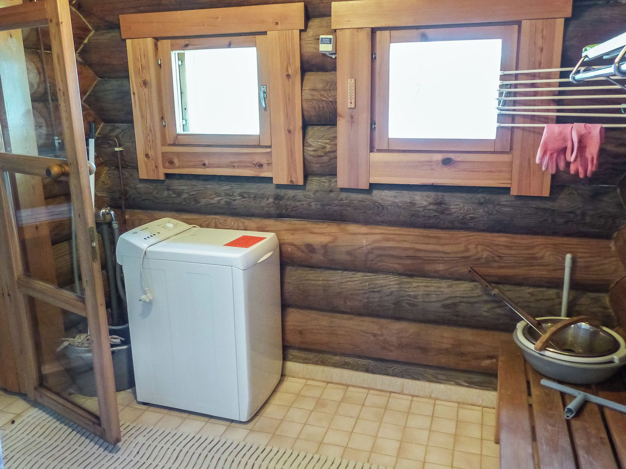 A compact room with a small white appliance, wooden walls, and a window.