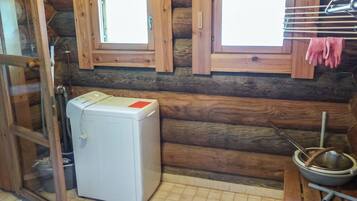 A compact room with a small white appliance, wooden walls, and a window.