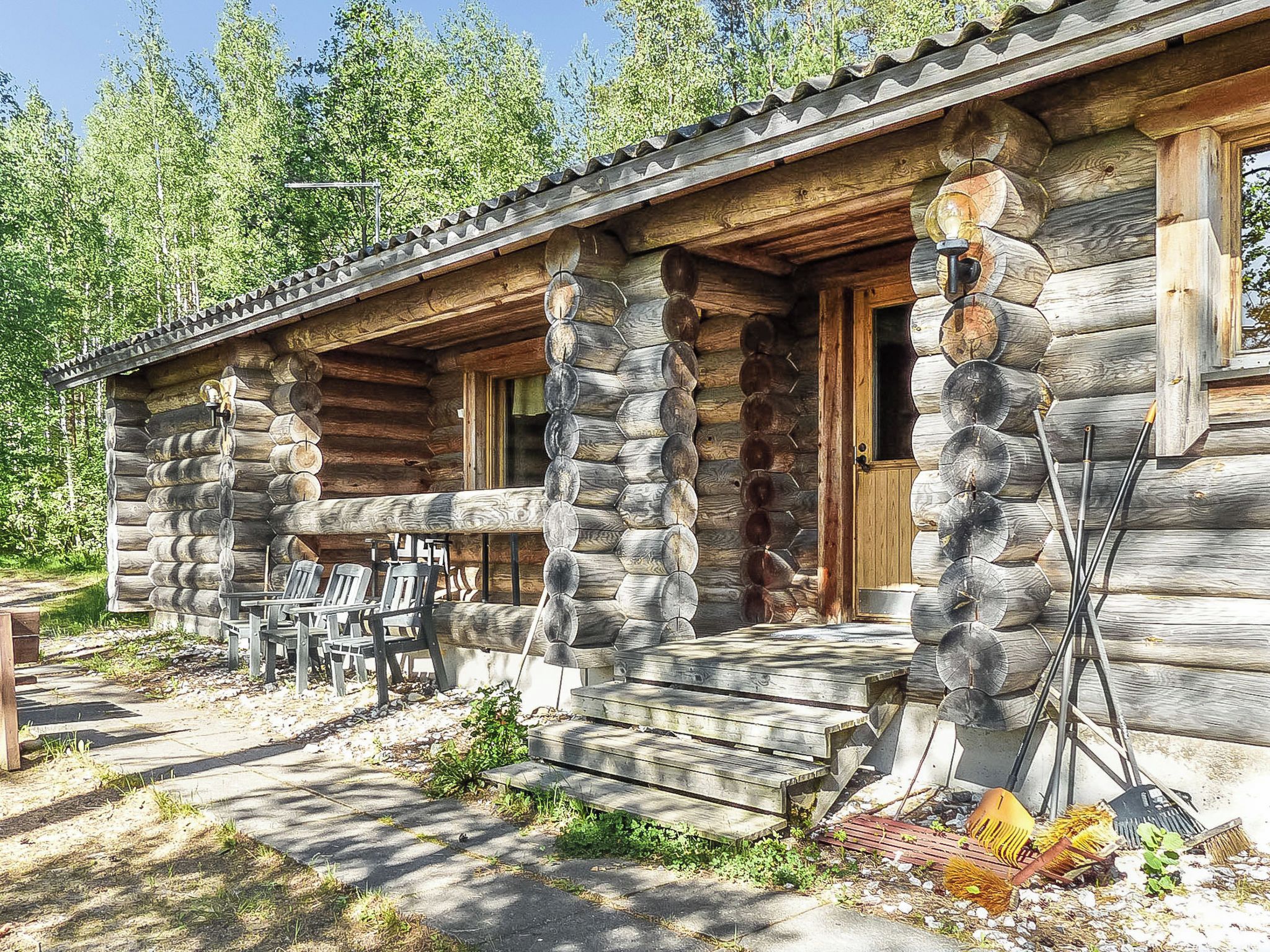 A log cabin with a porch, outdoor seating, and a door.