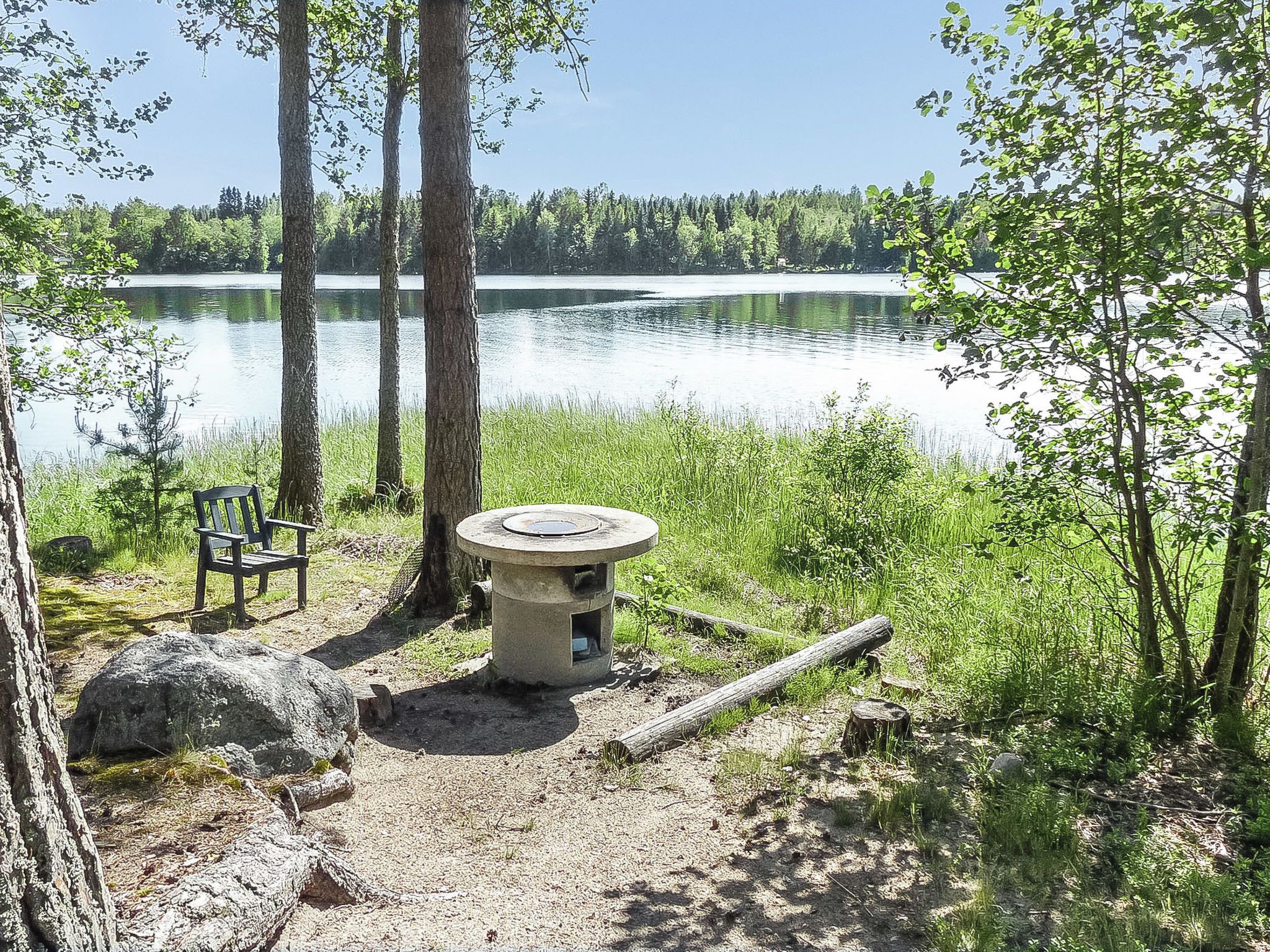 A lakeside campsite with a bench, a fire pit, and a view of the lake.