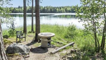 A lakeside campsite with a bench, a fire pit, and a view of the lake.