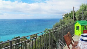 A balcony with a view of the sea, a small green playhouse, and a table with chairs. - Stunning private villa for 6 people with A/C, WIFI, TV, patio and pets allowed (Cervo)