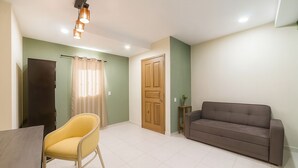 A room with a dining table, a yellow chair, a brown sofa, a wooden door, and a curtain. - Casa Santa Fe, Guanajuato (Guanajuato)