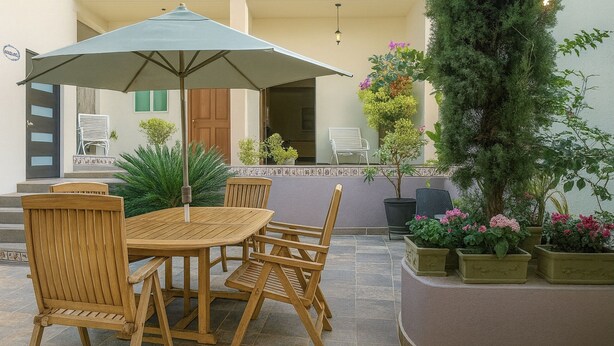 A patio with a wooden table and chairs, a large umbrella, and potted plants. - Casa Santa Fe, Guanajuato (Guanajuato)