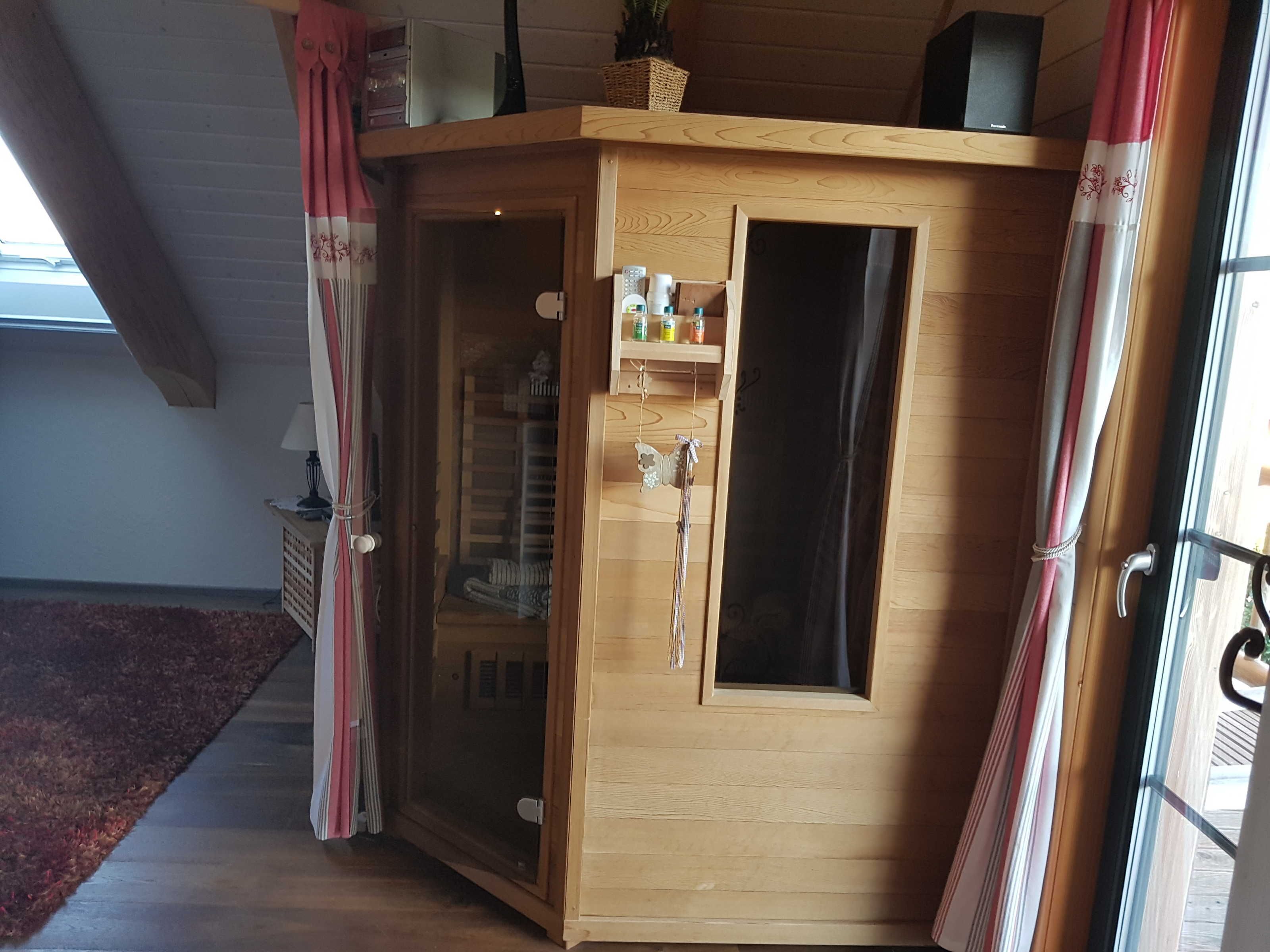A wooden cabinet with a glass door, a shelf with bottles, and a small window.