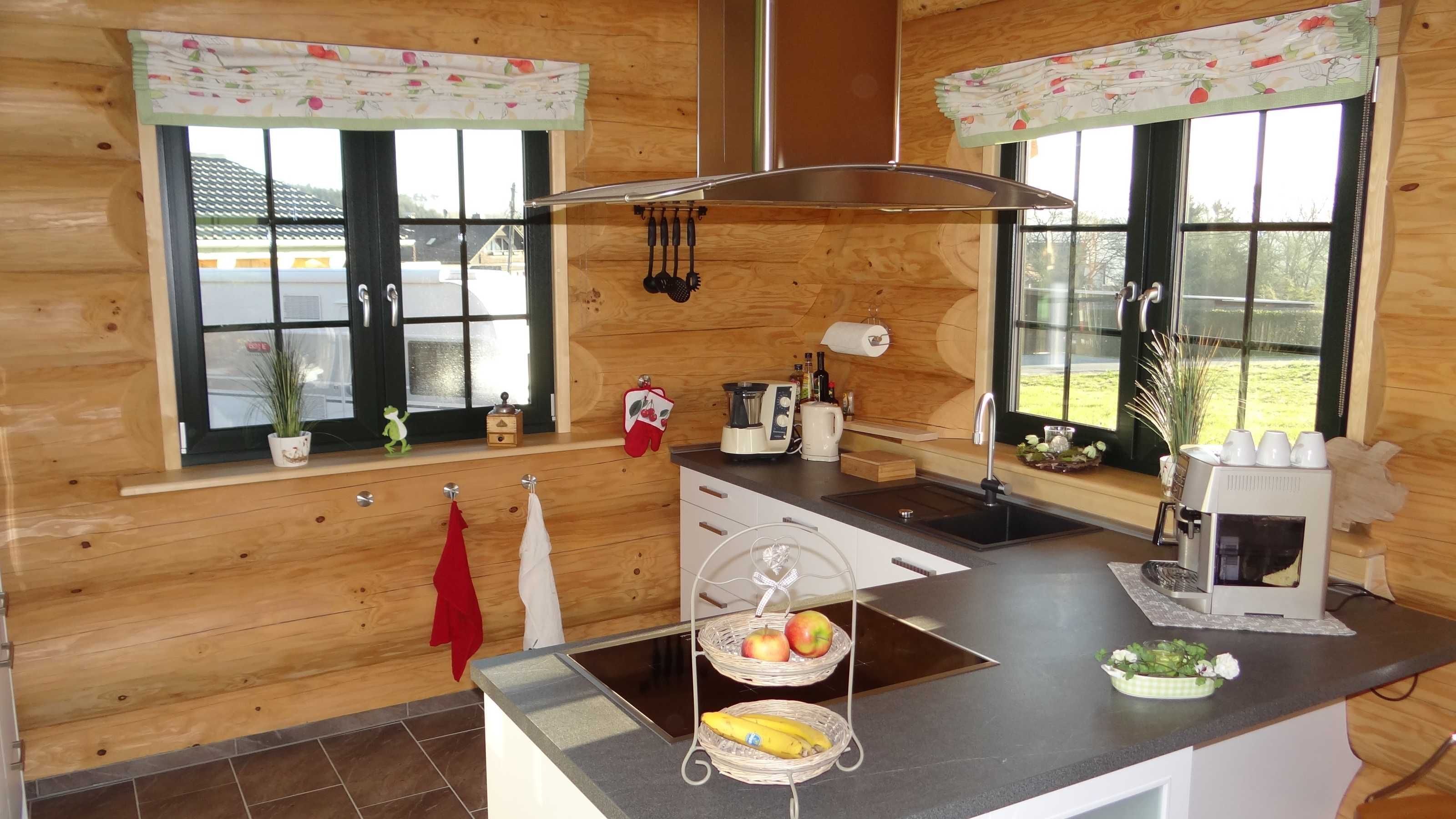 A modern kitchen with wooden walls, a black countertop, and a window with a view of a house.