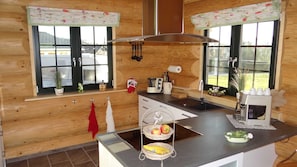 Una cocina moderna con paredes de madera, una encimera negra y una ventana con vistas a una casa.