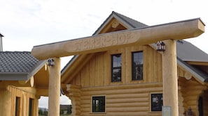 Una cabaña de troncos con un letrero llamativo de 'Sterehof', varias ventanas y un techo inclinado.