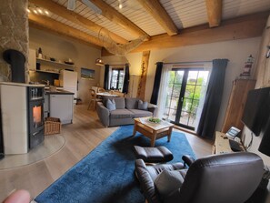A cozy living room with a fireplace, a sofa, a coffee table, and a television. - Fischerhütte - Steirer-Hof (Vöhl)