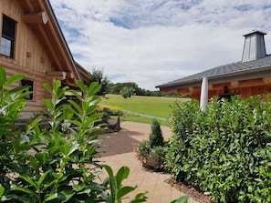 A wooden cabin with a paved pathway leading to a grassy field.