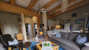 A cozy living room with a fireplace, a sofa, a coffee table, and a dining area visible in the background.