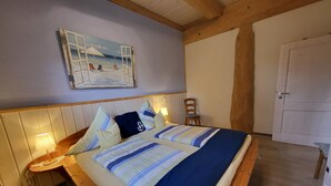 A bed with a striped bedspread, a wooden headboard, and a painting of a beach scene above it.
