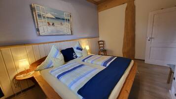 Ein Bett mit gestreifter Bettdecke, einem Holzkopfende und einem Bild einer Strandlandschaft darüber.