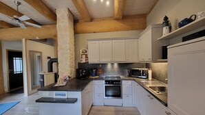 A modern kitchen with white cabinets, a central island, a built-in oven, a microwave, and a coffee maker.