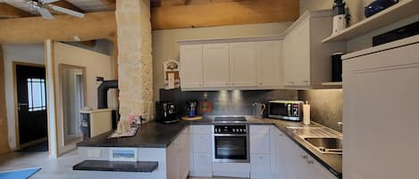 Una cocina moderna con armarios blancos, una isla central, horno empotrado, microondas y cafetera.