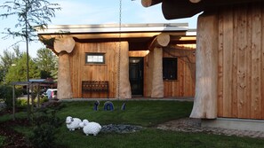 Une maison moderne en bois, dotée d’une grande véranda, d’une petite fenêtre et d’une porte.