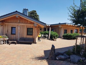Una cabaña de estilo rústico con un patio de ladrillo, un banco y macetas con plantas.