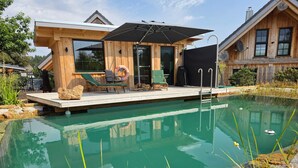 Una cabana de fusta amb piscina, mobiliari d'exterior i un porxo cobert.