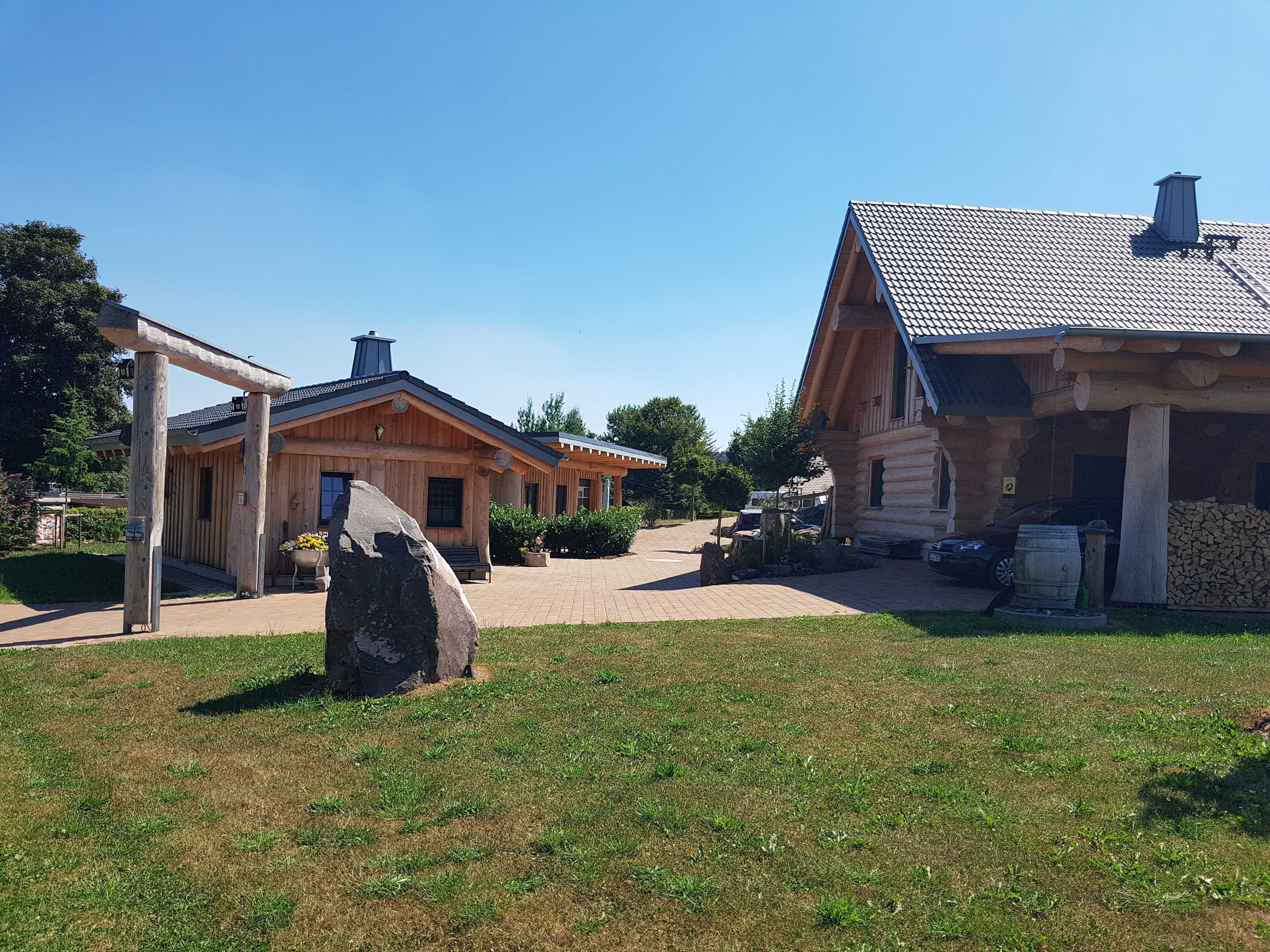 A wooden cabin with a porch and a stone in the foreground.