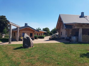 A wooden cabin with a porch and a stone in the foreground.