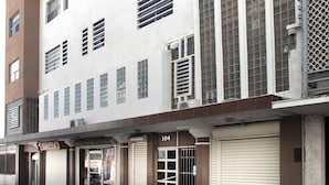 A multi-story building with a white facade, multiple windows, and a storefront with closed shutters. - Hotel Allende 104 (Chihuahua)