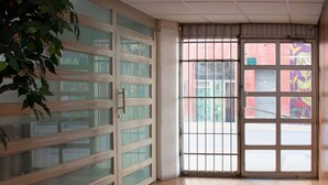 A room with a large sliding glass door leading to a street view, a tiled floor, and a potted plant. - Hotel Allende 104 (Chihuahua)
