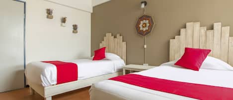 Habitación de hotel con dos camas, cada una con ropa de cama blanca y almohadas rojas, cabeceros de madera y un tapiz decorativo.