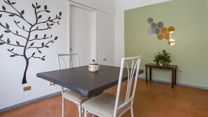 A dining area with a table, chairs, a decorative wall, and a small plant. - Hotel Allende 104 (Chihuahua)